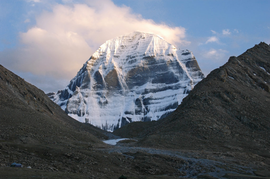 The peak of the sacred mount Kailash lit by the sun on background white cloud, Tibet, China