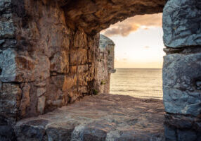 old ruins background with scenic sunset over sea through ancient